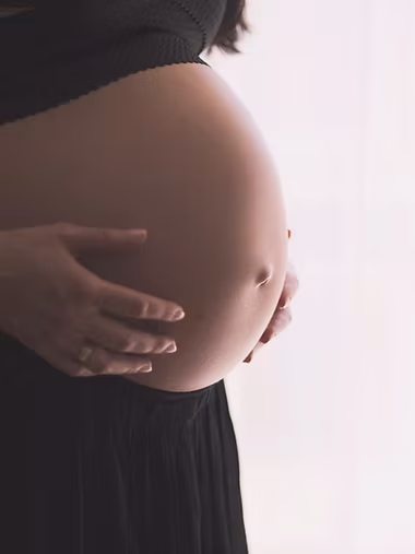 Gestante com as mãos apoiadas sobre a barriga
